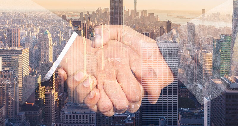 A handshake overlaid a city skyline concept image